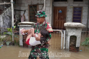 Seorang Babinsa Koramil 12/Rajeg menggendong anak kecil melewati banjir di Desa Mekarsari, Tangerang, dalam upaya evakuasi warga terdampak.