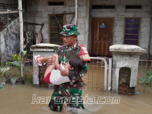 Seorang Babinsa Koramil 12/Rajeg menggendong anak kecil melewati banjir di Desa Mekarsari, Tangerang, dalam upaya evakuasi warga terdampak.