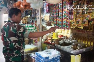 Anggota Babinsa TNI AD sedang berdialog dengan pedagang pasar dan mengecek stok minyak goreng dalam plastik di pasar tradisional Bekasi.