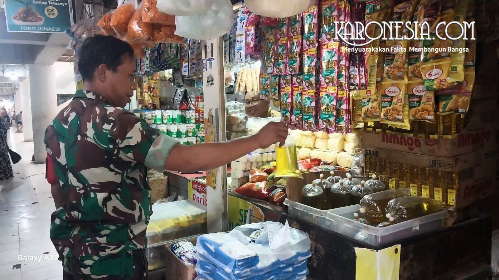 Anggota Babinsa TNI AD sedang berdialog dengan pedagang pasar dan mengecek stok minyak goreng dalam plastik di pasar tradisional Bekasi.