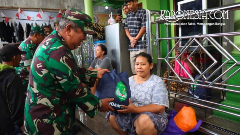 Personel TNI Kodim 0504 Jakarta Selatan menyerahkan bantuan tas biru berisi sembako kepada seorang warga wanita di Pejaten Timur saat banjir.