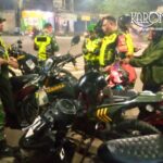 Personel Babinsa Koramil 05/Bantar Gebang bersama Komduk sedang berkoordinasi di samping sepeda motor dinas saat patroli malam di Bekasi.
