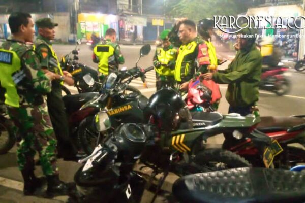 Personel Babinsa Koramil 05/Bantar Gebang bersama Komduk sedang berkoordinasi di samping sepeda motor dinas saat patroli malam di Bekasi.