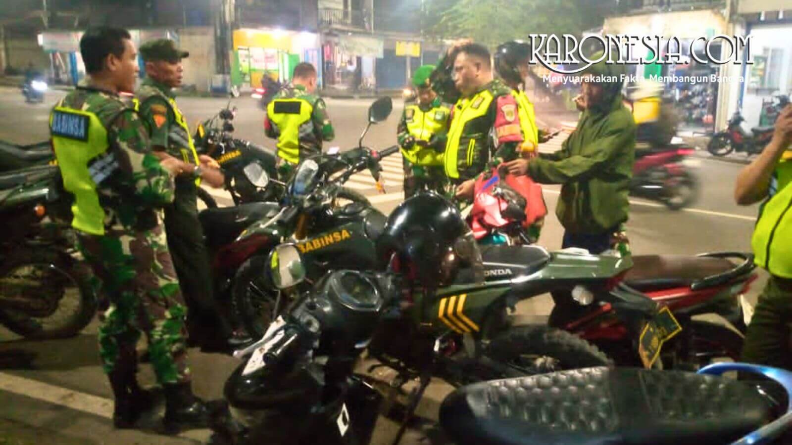 Personel Babinsa Koramil 05/Bantar Gebang bersama Komduk sedang berkoordinasi di samping sepeda motor dinas saat patroli malam di Bekasi.
