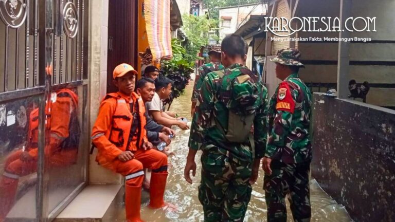 Personel TNI Babinsa dan petugas BPBD berbaju oranye sedang memantau kondisi banjir di pemukiman warga Bidara Cina Jakarta Timur.