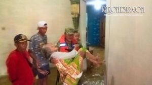 Anggota Babinsa mengevakuasi lansia di tengah banjir Bekasi.