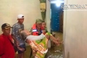 Anggota Babinsa mengevakuasi lansia di tengah banjir Bekasi.