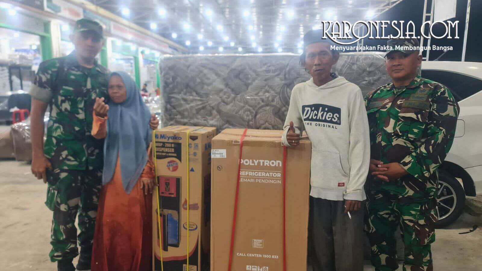Bapak Sudrajat dan istri berfoto bersama anggota TNI di samping bantuan kulkas, dispenser, dan kasur.