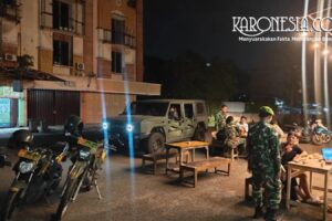 Babinsa Koramil Kranji menyapa warga saat patroli malam menggunakan kendaraan Maung dan motor dinas di Bekasi.