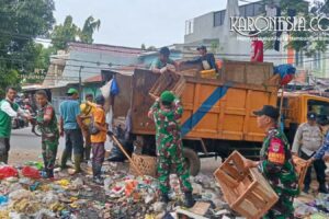 Personel TNI Koramil 01 Tangerang bersama warga gotong royong mengangkut tumpukan sampah ke dalam truk di Karawaci.