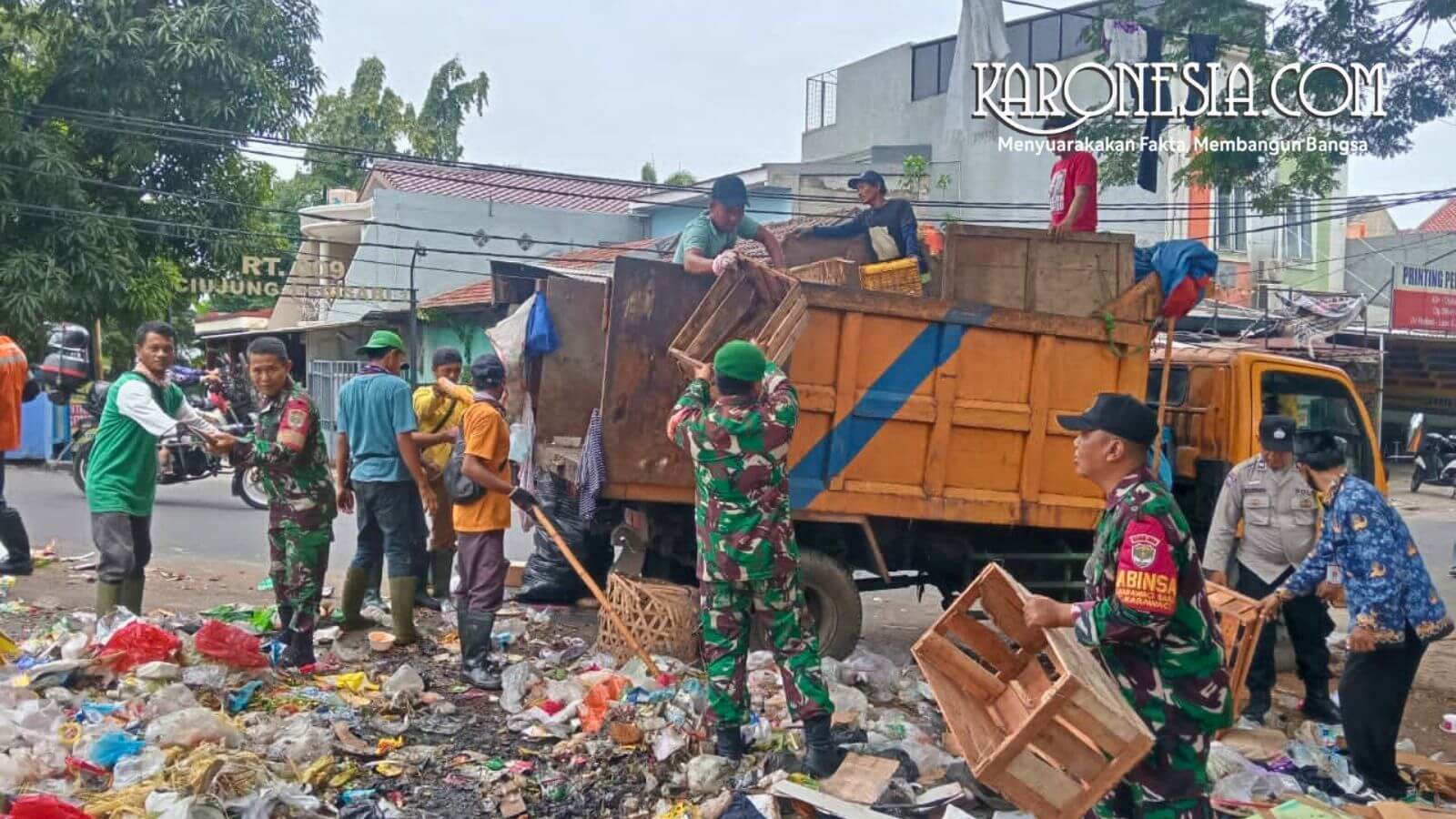 Personel TNI Koramil 01 Tangerang bersama warga gotong royong mengangkut tumpukan sampah ke dalam truk di Karawaci.