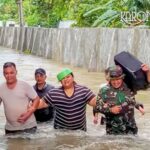 Personel Babinsa TNI membantu warga berjalan melewati banjir di Kelurahan Gembor Kota Tangerang.