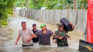 Personel Babinsa TNI membantu warga berjalan melewati banjir di Kelurahan Gembor Kota Tangerang.