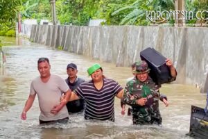 Personel Babinsa TNI membantu warga berjalan melewati banjir di Kelurahan Gembor Kota Tangerang.