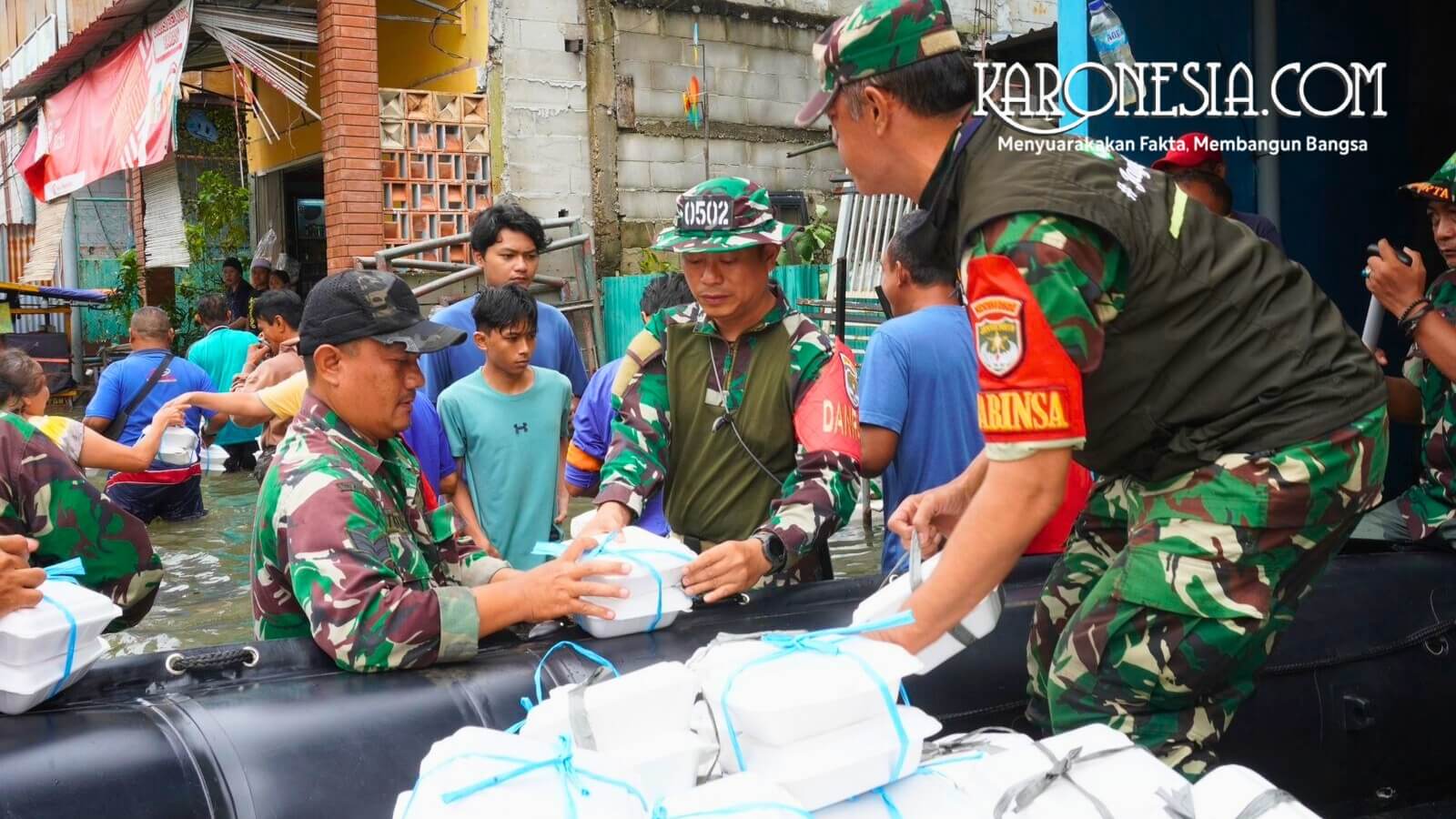 Anggota Babinsa Kodim 0502 Jakarta Utara menurunkan bantuan logistik makanan untuk warga terdampak banjir.