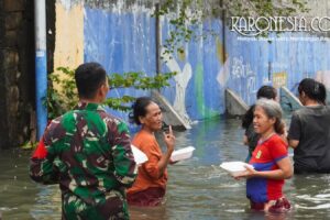 Prajurit TNI Kodam Jaya berinteraksi dengan warga saat distribusi bantuan makanan di lokasi banjir Kapuk Muara.