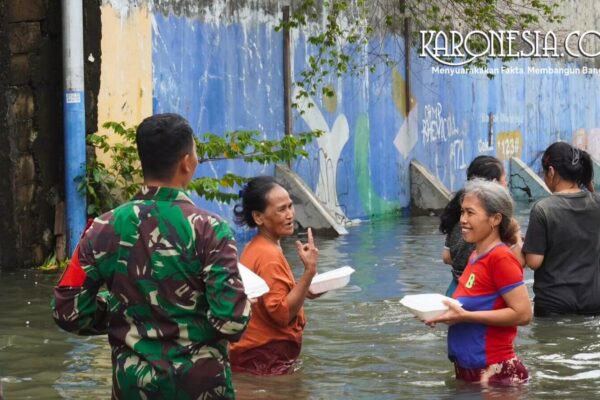 Prajurit TNI Kodam Jaya berinteraksi dengan warga saat distribusi bantuan makanan di lokasi banjir Kapuk Muara.
