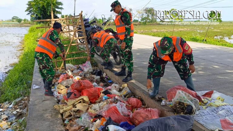 Personel Koramil 08/Kronjo membersihkan sampah di pinggir jalan desa.