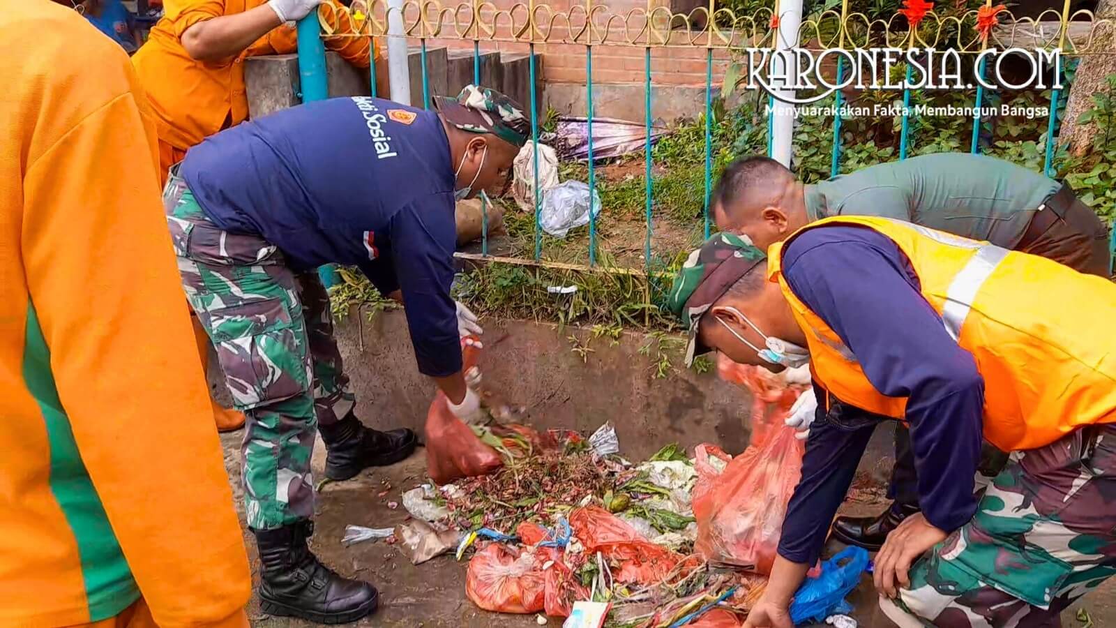 Prajurit memungut sampah di selokan.