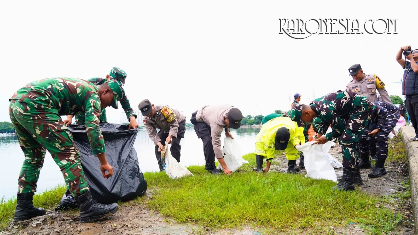 Personel TNI-Polri bersama petugas dan warga memungut sampah di tepi Waduk Danau Cincin, Tanjung Priok, dalam kegiatan Jaga Jakarta Bersih.