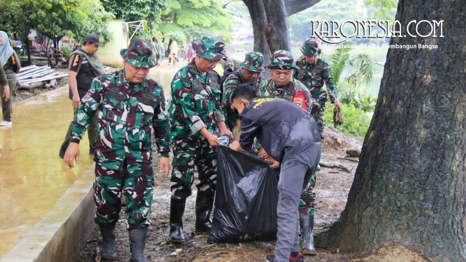 Personel gabungan mengangkat sampah plastik di tepian Danau Duta Harapan Bekasi