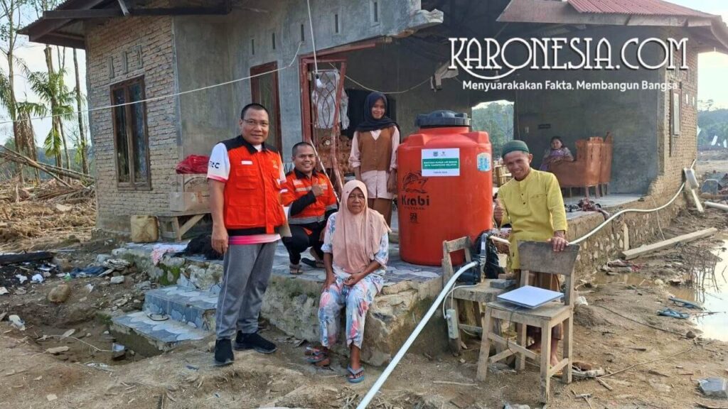 Relawan Baznas Tangsel bersama warga di depan rumah bantuan dan tangki air bersih korban banjir Aceh Tamiang