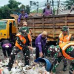 Personel TNI Koramil Cisoka bersama warga mengangkut sampah di Jalan Raya Serang Desa Cikande Kabupaten Tangerang