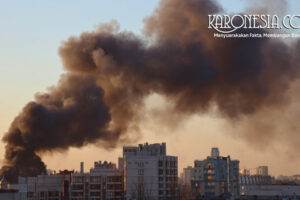 Asap tebal membubung di udara sebagai ilustrasi konflik dan serangan udara di kawasan perkotaan.