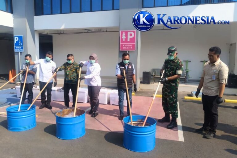 Petugas Forkopimda Bekasi memasukkan barang bukti narkotika ke dalam tong untuk dimusnahkan.