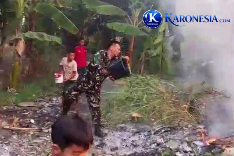 Babinsa Serka Amran Simangunsong menyiramkan air dari ember ke lahan terbakar.