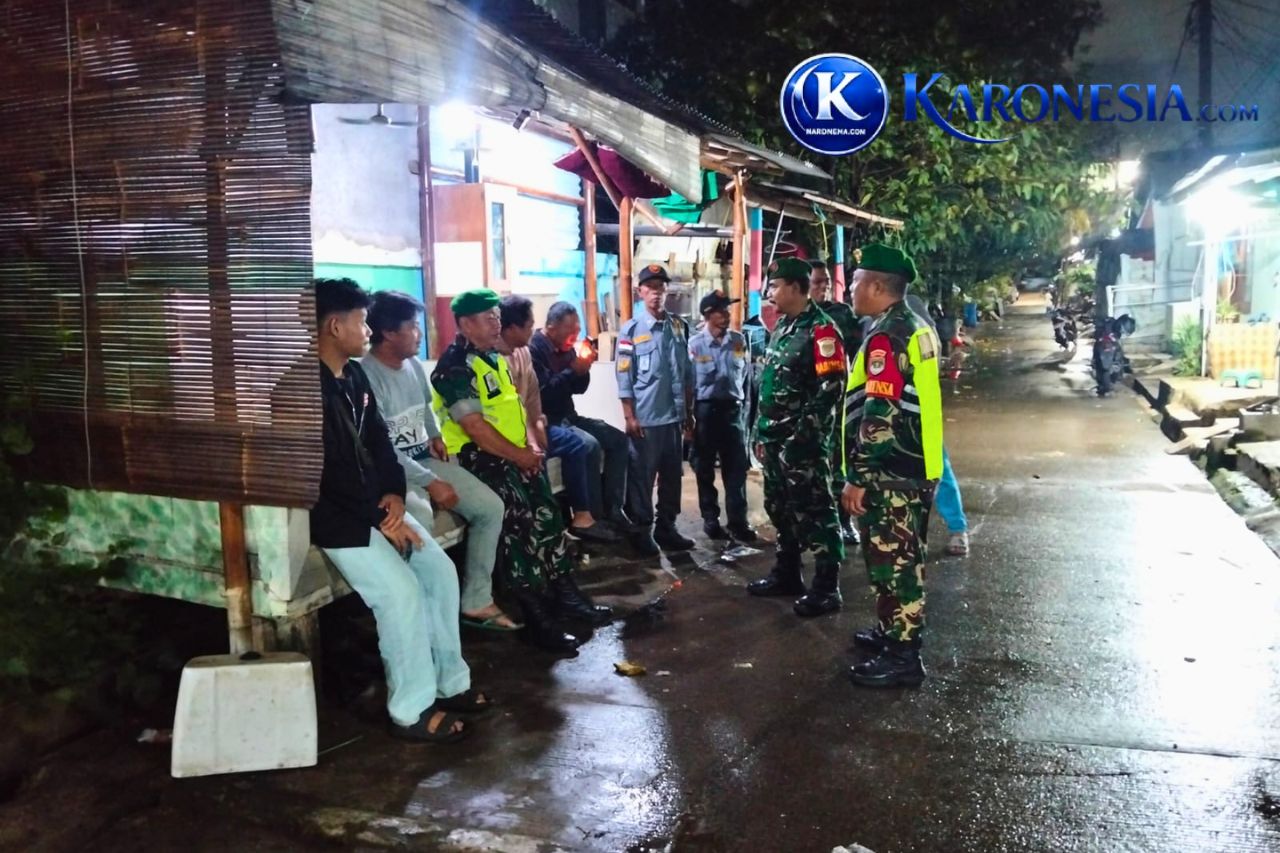 Babinsa Koramil Jati Asih dan Linmas berdialog dengan warga saat patroli malam