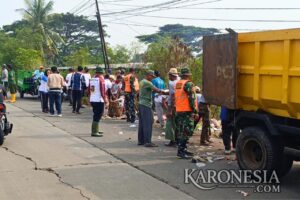 Personel TNI dan warga bersihkan tumpukan sampah di Jalan Raya Pasilian, Kronjo.