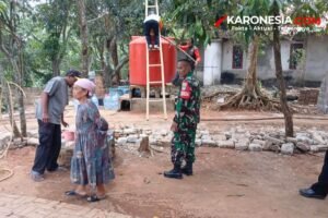 Anggota TNI berseragam loreng berdiri di dekat tandon air merah saat warga menerima bantuan air bersih Koramil 03/Serpong di Tangerang Selatan