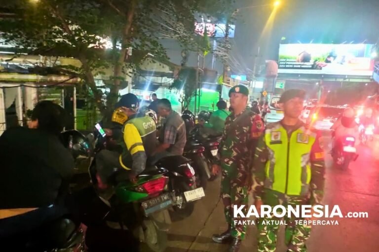 Personel TNI berseragam loreng dan petugas Satpol PP berompi kuning-hijau berdiri di pinggir jalan saat patroli gabungan malam hari di Kota Bekasi