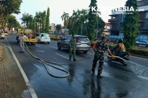 Babinsa Sertu Hamzah menyiram ruas jalan di Serpong