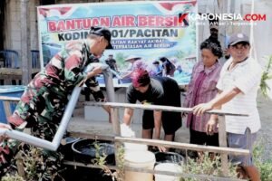 Prajurit TNI AD menyalurkan bantuan air bersih dengan selang ke wadah warga di depan spanduk Bantuan Air Bersih Kodim Pacitan, Korem 081/DSJ.