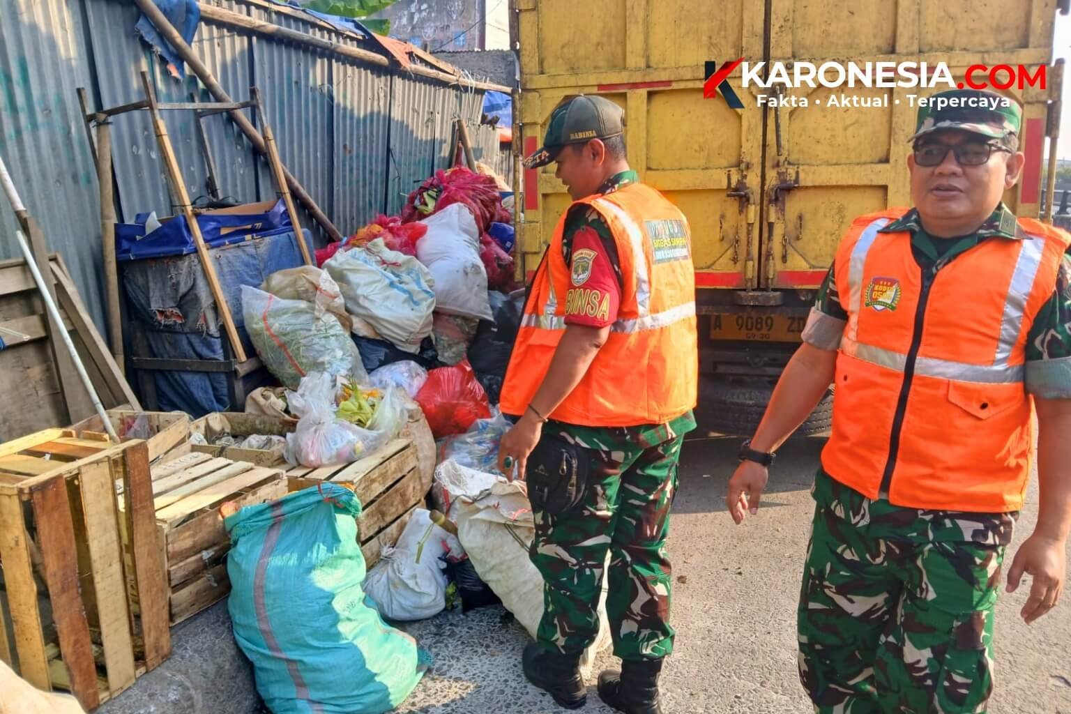Dua personel Koramil 05/Ciputat berompi oranye Satgas Sampah berdiri di dekat tumpukan sampah yang akan diangkut truk di Jalan H Usman, Ciputat