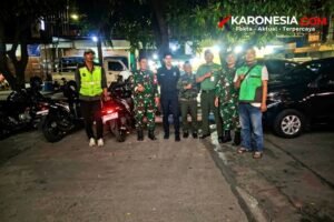 Personel TNI AD berseragam loreng bersama warga berompi hijau berfoto di sela patroli malam siskamling di Tangerang