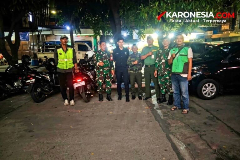 Personel TNI AD berseragam loreng bersama warga berompi hijau berfoto di sela patroli malam siskamling di Tangerang