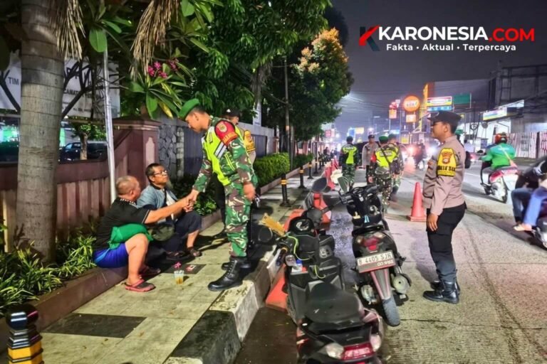Anggota Babinsa TNI AD berseragam loreng menyalami dua warga yang duduk di trotoar saat patroli siskamling malam hari bersama personel berseragam lain.