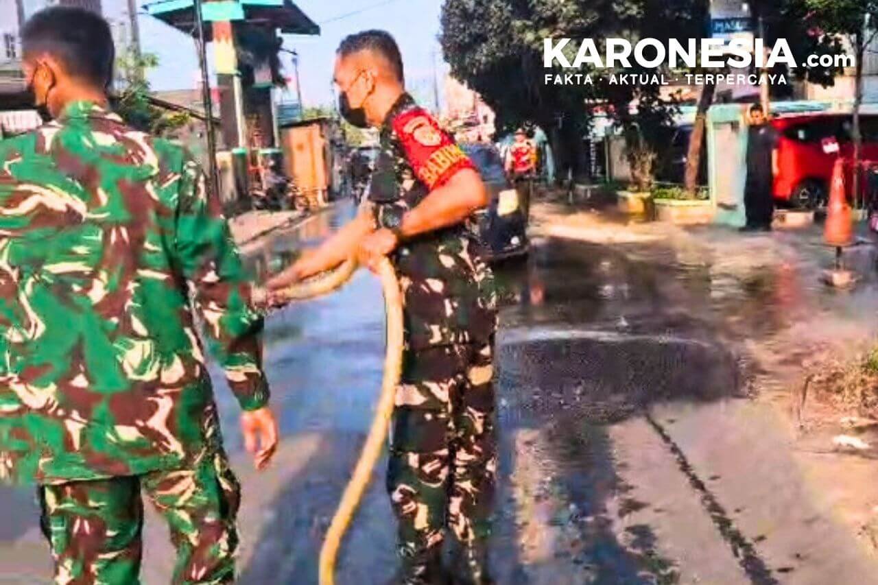 Sertu Hamzah menyiram jalan yang terdapat abu vulkanik di Serpong