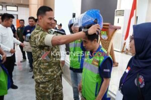 Dandim 0510/Tigaraksa Letkol Inf Yudha Fuady Putra memakaikan helm kepada pengemudi ojol dalam perayaan HUT ke-1 FORBETA di Tangerang.