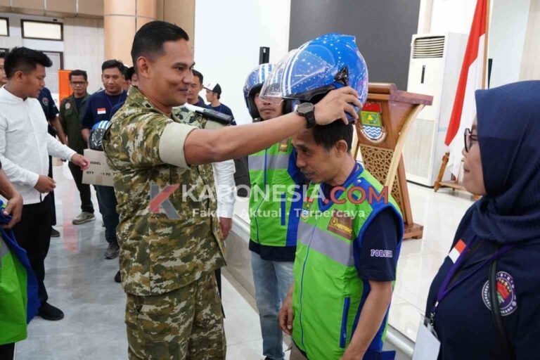 Dandim 0510/Tigaraksa Letkol Inf Yudha Fuady Putra memakaikan helm kepada pengemudi ojol dalam perayaan HUT ke-1 FORBETA di Tangerang.