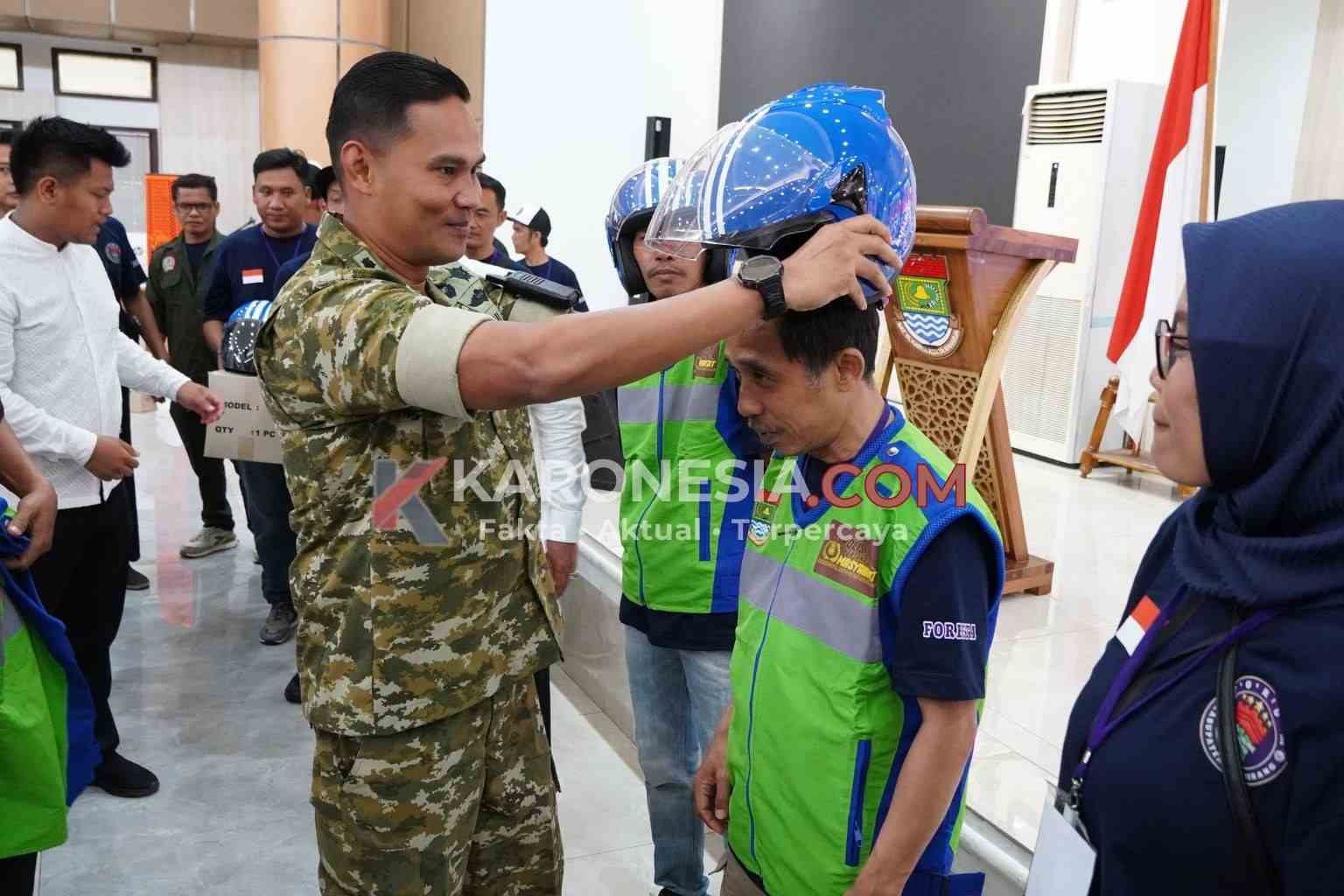 Dandim 0510/Tigaraksa Letkol Inf Yudha Fuady Putra memakaikan helm kepada pengemudi ojol dalam perayaan HUT ke-1 FORBETA di Tangerang.