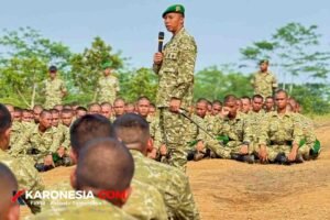 Danyonif TP 205/Gandamana memegang mikrofon dan tongkat komando saat memberi arahan Jam Komandan kepada prajurit yang duduk bersila di Jasinga