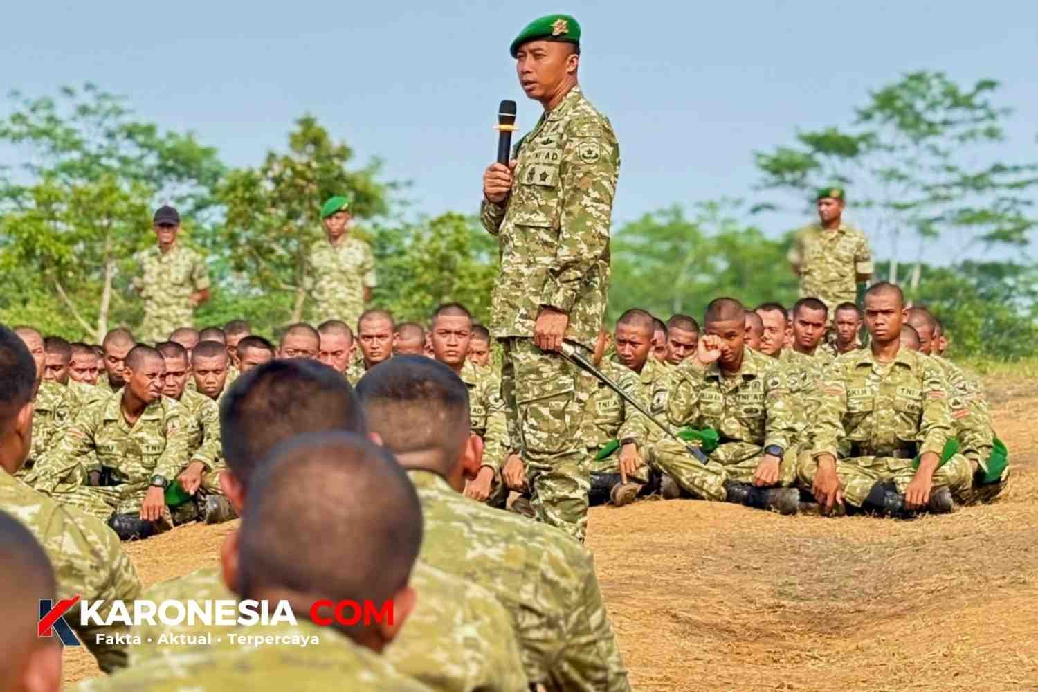 Danyonif TP 205/Gandamana memegang mikrofon dan tongkat komando saat memberi arahan Jam Komandan kepada prajurit yang duduk bersila di Jasinga