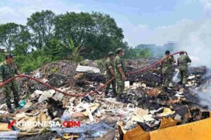 Personel Koramil 03/Legok menyemprotkan air dengan selang saat memadamkan kebakaran tumpukan sampah di Pagedangan, Tangerang
