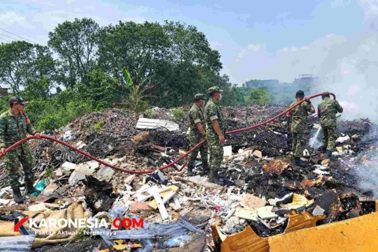 Personel Koramil 03/Legok menyemprotkan air dengan selang saat memadamkan kebakaran tumpukan sampah di Pagedangan, Tangerang