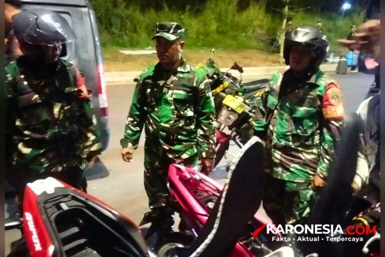 Personel Koramil 03/Legok berseragam loreng berdiri di tepi jalan saat patroli malam hari di Kecamatan Legok
