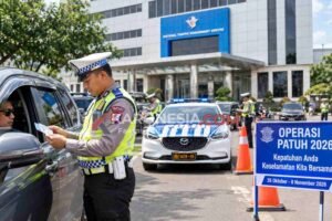 Polisi lalu lintas sedang memeriksa surat kendaraan seorang pengemudi mobil saat operasi kepatuhan lalu lintas 2026 di depan gedung National Traffic Management Centre.